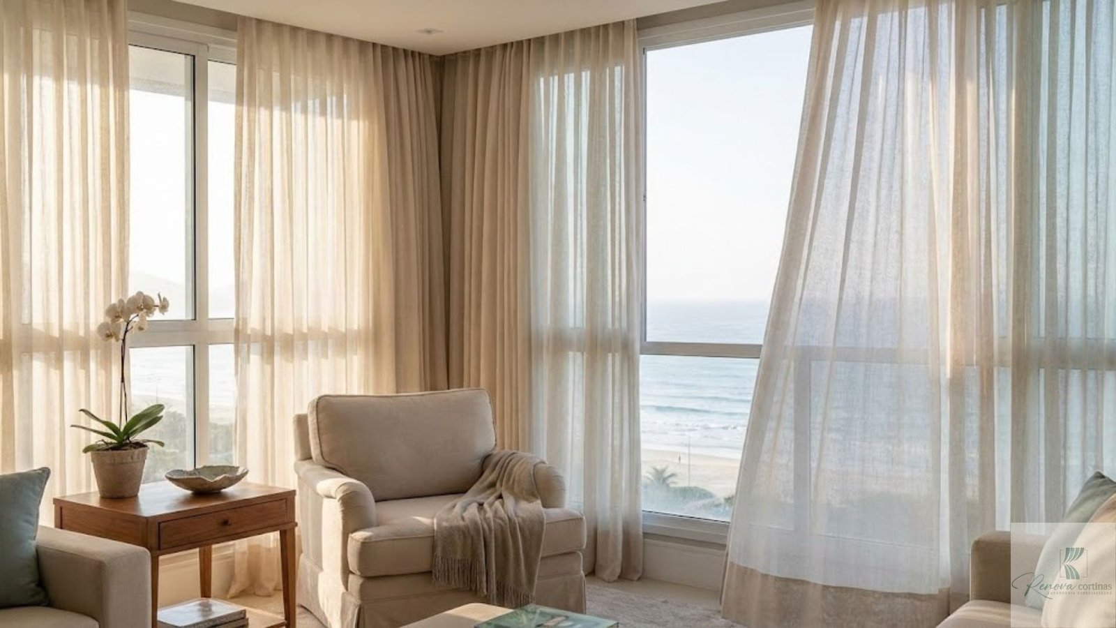 Fotografia realista de uma sala de estar luxuosa com vista para o mar, destacando cortinas claras de tecido nobre filtrando a luz do sol. A imagem ilustra a constante exposição das fibras naturais ao clima litorâneo, reforçando a importância da lavagem de cortinas em Itapema para proteger a decoração de alto padrão contra a oxidação, os raios UV e os danos causados pela maresia.
